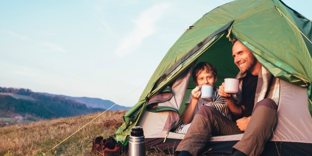 Couple in a tent drinking a beverage from mugs